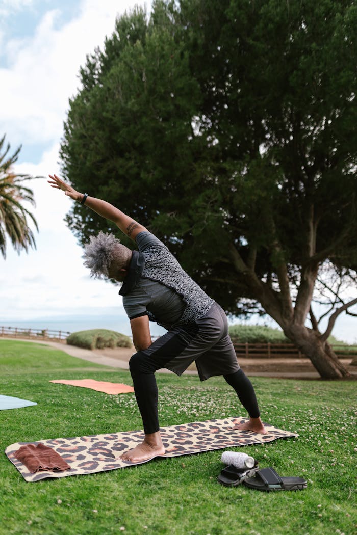 Man performing a yoga pose outdoors in a park, embracing wellness and nature.